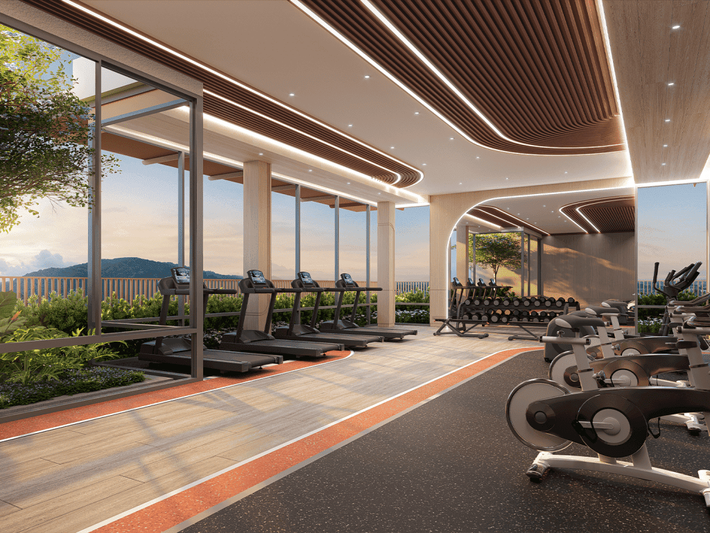Gym interior with cardio equipment and large windows overlooking lush landscape in Phuket, Thailand.