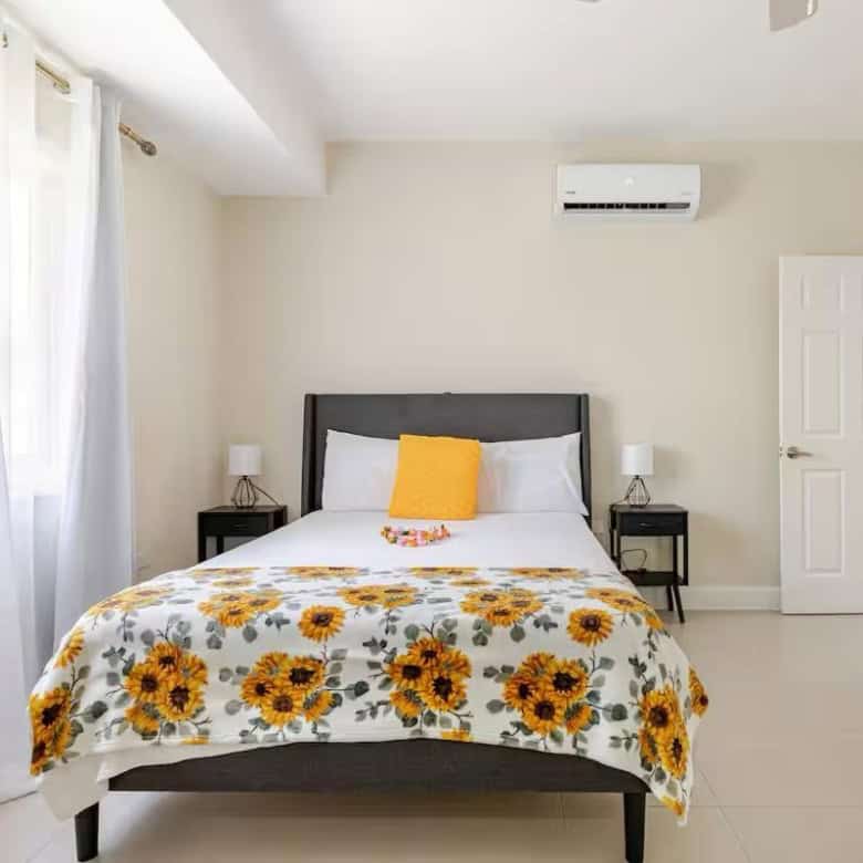 Modern bedroom with sunflower bedding in a bright, airy Jamaican home.