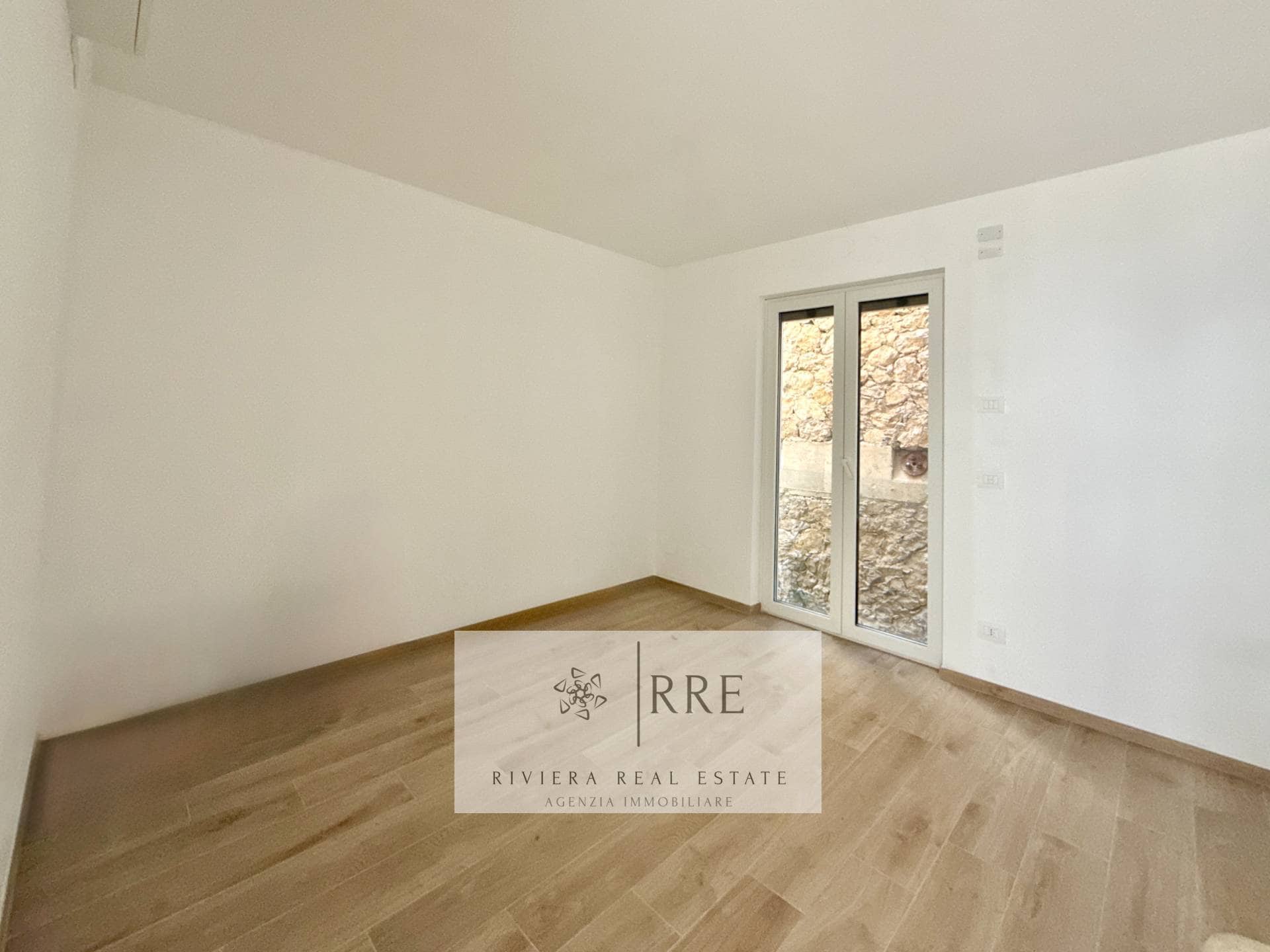 Empty room with large window and wooden floor for sale in international property listings.
