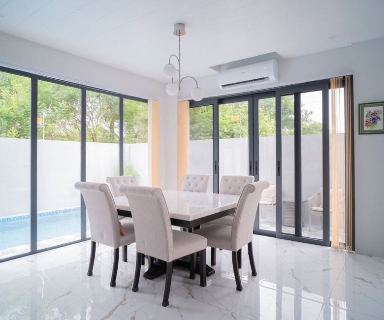Elegant dining room with large glass doors overlooking the pool and garden. Perfect for family meals.