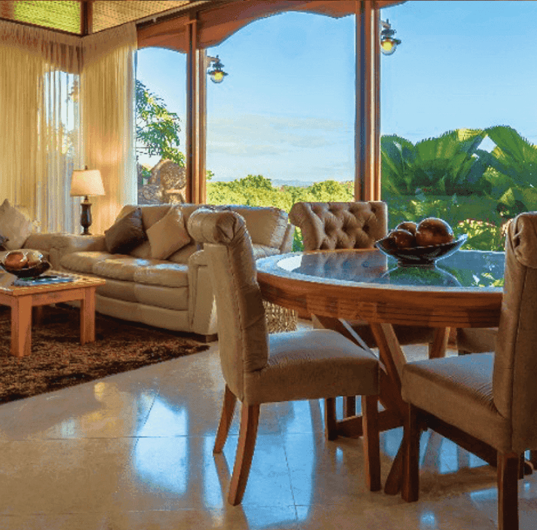 Spacious living room with large windows overlooking lush Costa Rican landscape. Comfortable furnitur.
