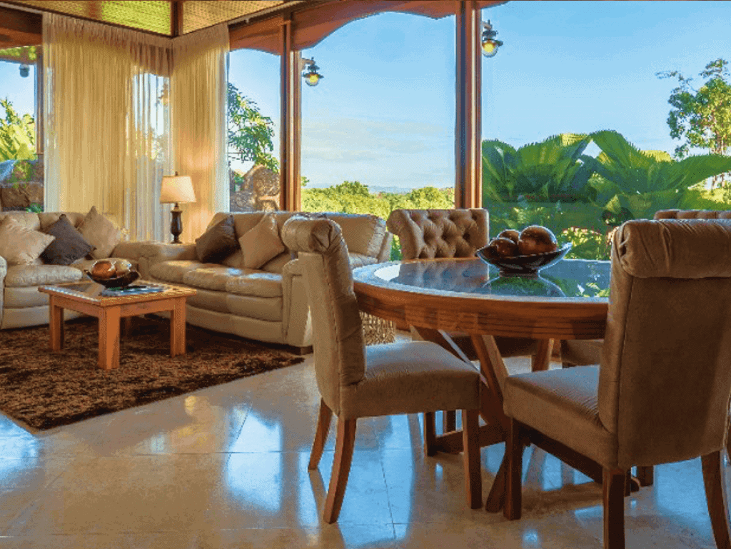 Spacious living room with large windows overlooking lush Costa Rican landscape. Comfortable furnitur.