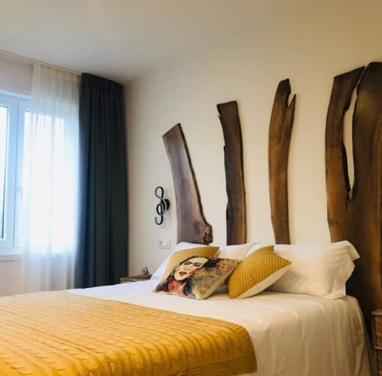 Elegant hotel bedroom with rustic wooden headboard in Leon, Spain.