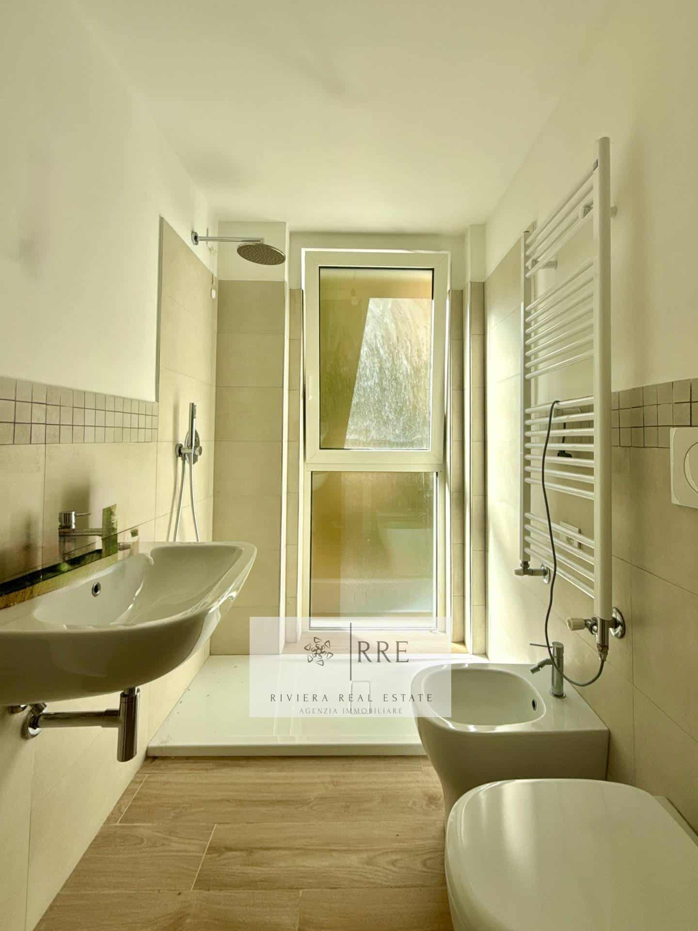Bright bathroom featuring a large window, modern sink, and heated towel rail.