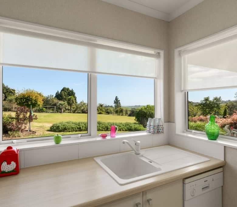 Bright kitchen with large windows overlooking lush gardens and scenic landscape in Tauranga, New Zea.
