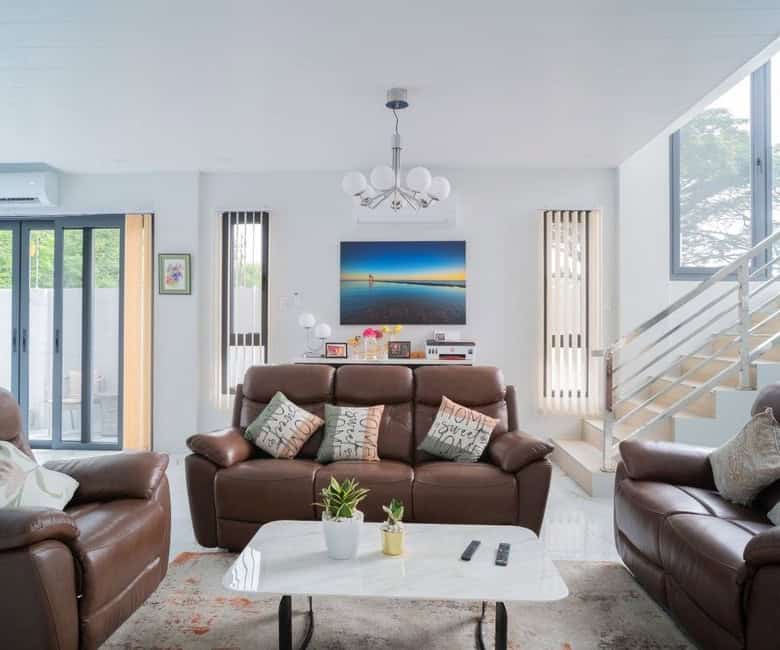 Spacious living room with leather sofas, modern decor, and large windows in Dasmarinas, Philippines.