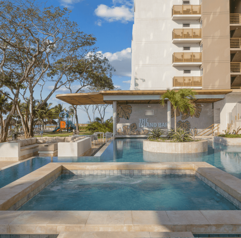 Modern pool area at Surfside Playa Caracol, Panama, with lush landscaping and ocean views.