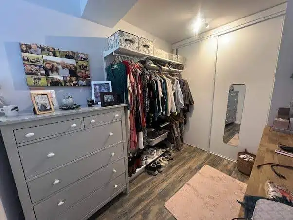 Interior of a bedroom showing a wardrobe, dresser, and personal belongings in a renovated village ho.
