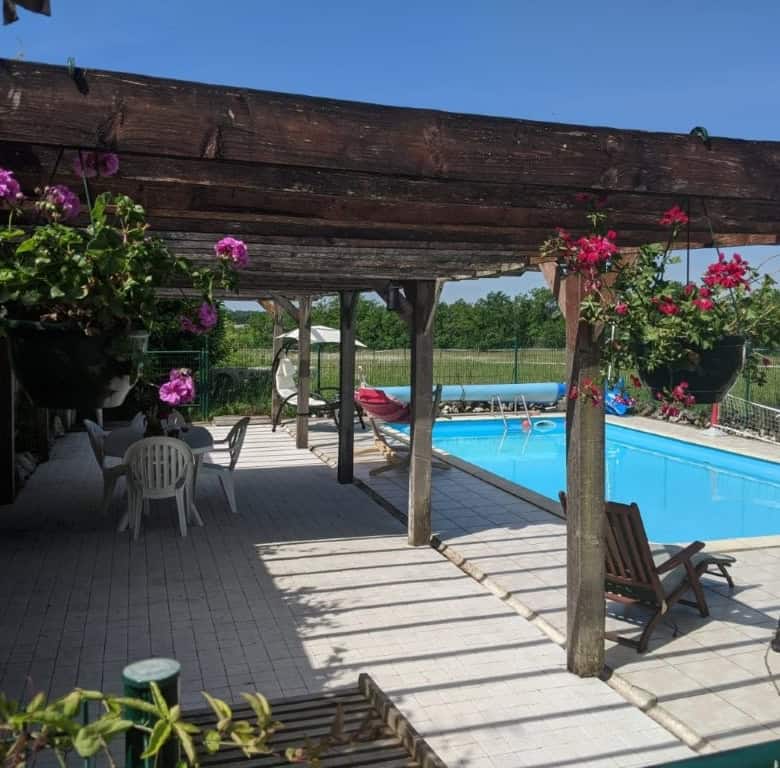 Elegant outdoor pool area with shaded seating and garden views in Chatignac, France.