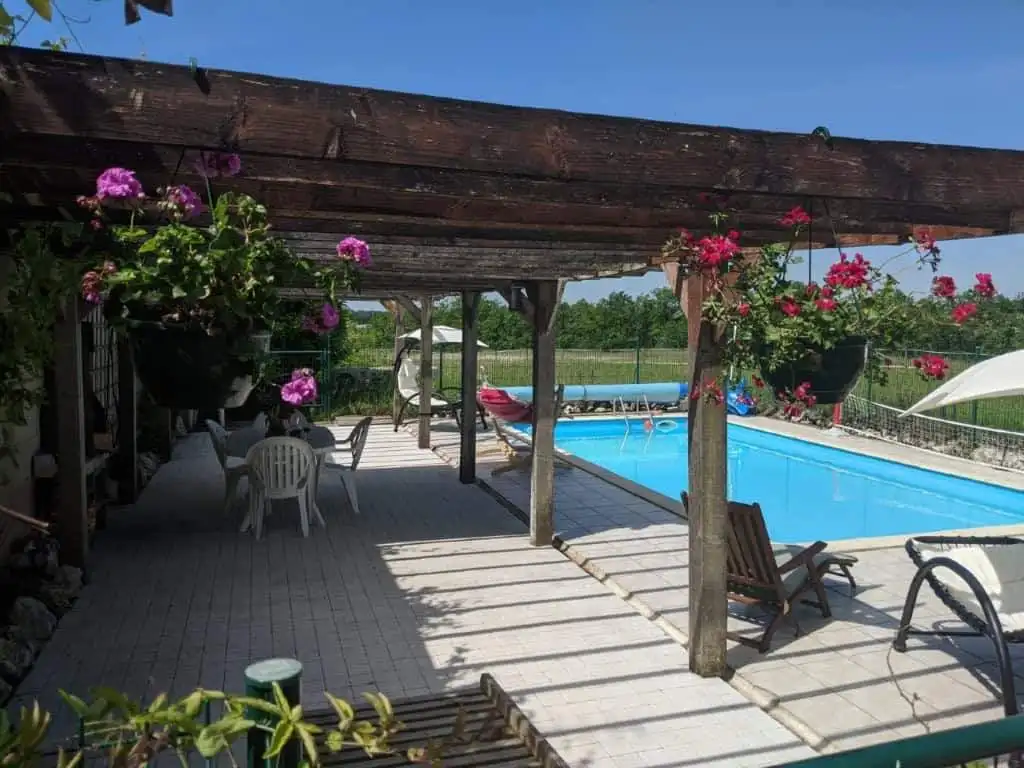 Elegant outdoor pool area with shaded seating and garden views in Chatignac, France.