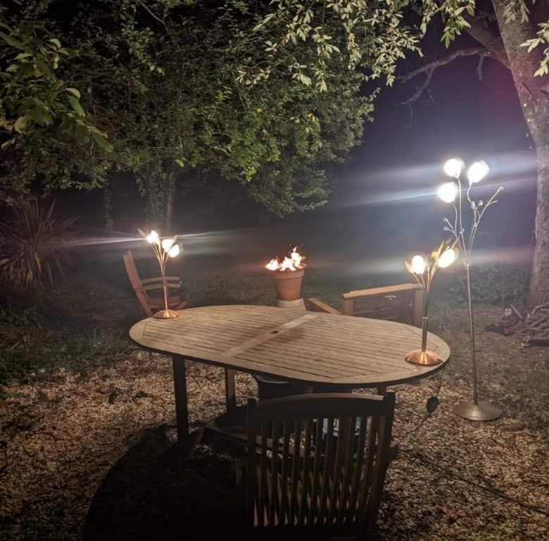 Elegant outdoor dining area with lighting in a lush garden setting in France.