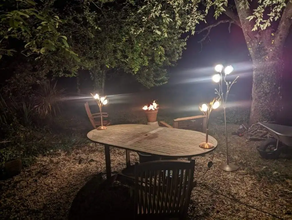 Elegant outdoor dining area with lighting in a lush garden setting in France.