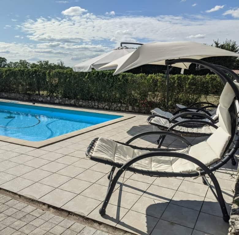 Poolside lounge chairs with umbrella at a luxurious property in France.