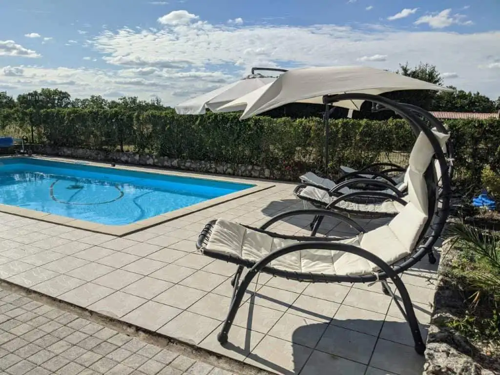 Poolside lounge chairs with umbrella at a luxurious property in France.