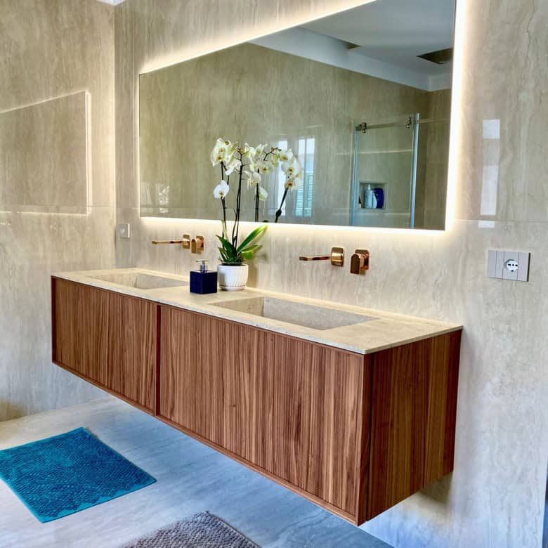 Modern bathroom with wooden vanity and large mirror.