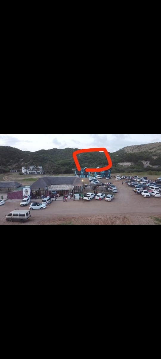 Beachfront property with parking area and scenic hills. Beachfront property with parking lot and scenic hills in the background.