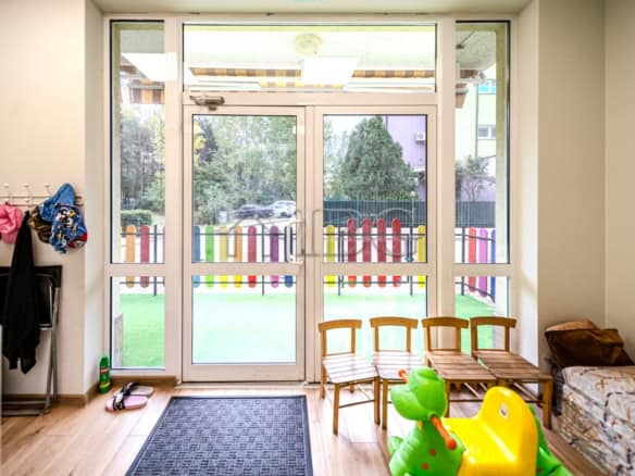 Bright indoor play space with large glass doors and outdoor garden view.