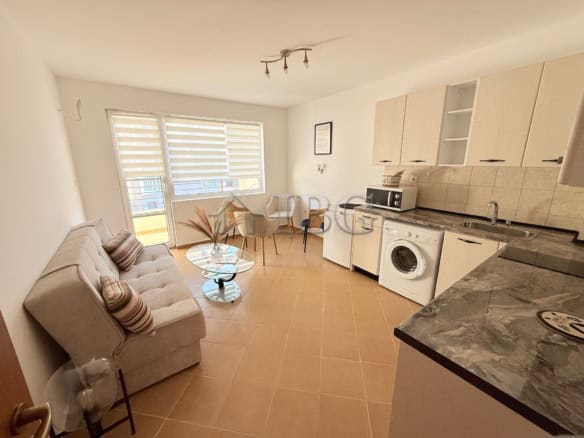 Spacious living room with sofa and dining area in a sunny apartment close to the sea.