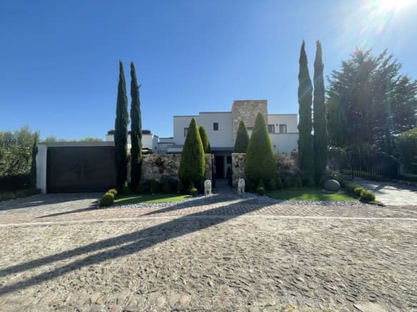 Elegant villa with tall cypress trees and a well-maintained garden.