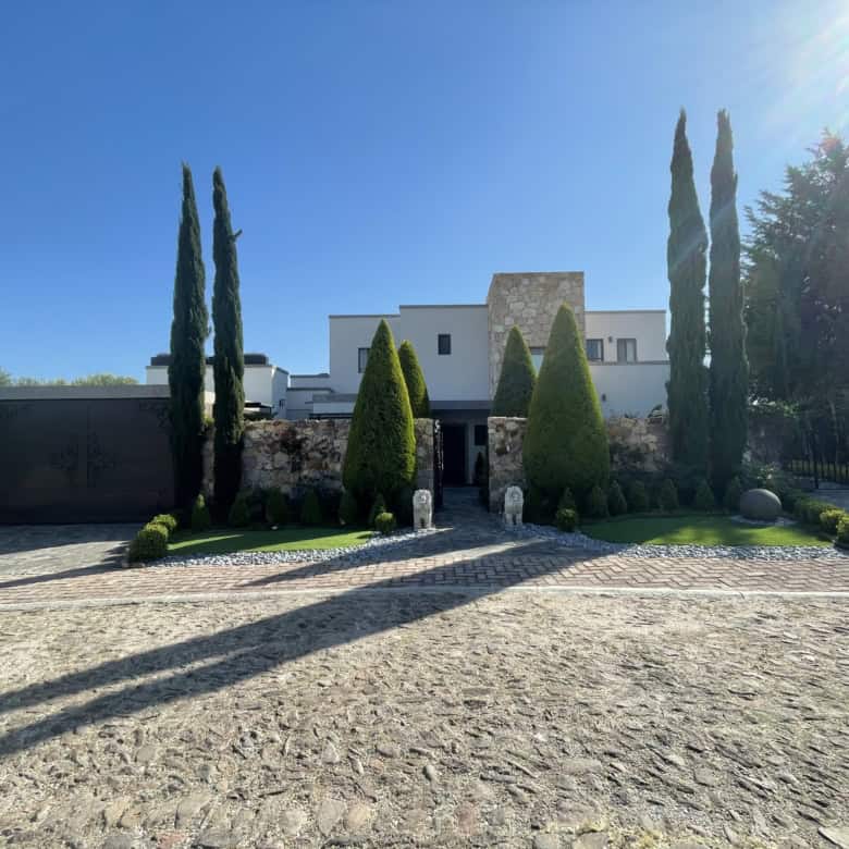 Elegant villa with tall cypress trees and a well-maintained garden.