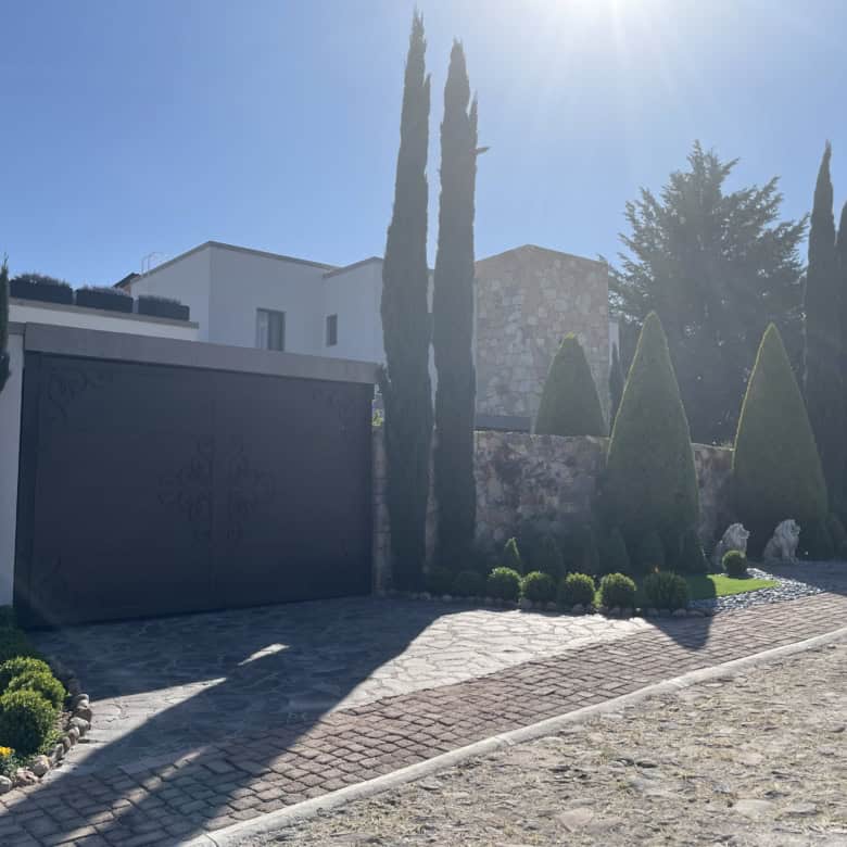 Elegant villa with landscaped garden, tall cypress trees, and modern architecture.