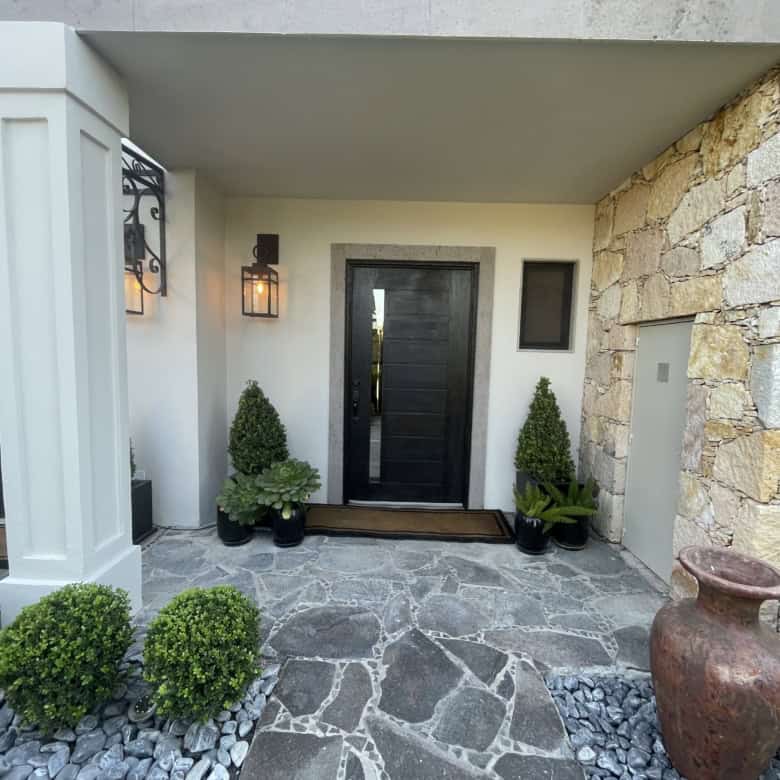 Modern villa entrance with black door and stone accents.