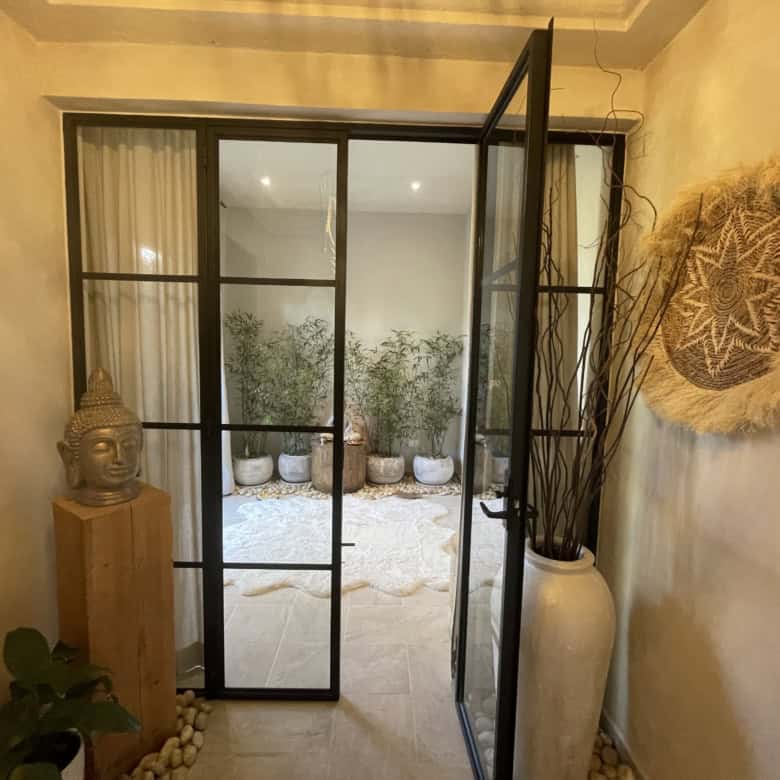 Elegant glass door leading to a serene outdoor patio with potted plants and natural decor.