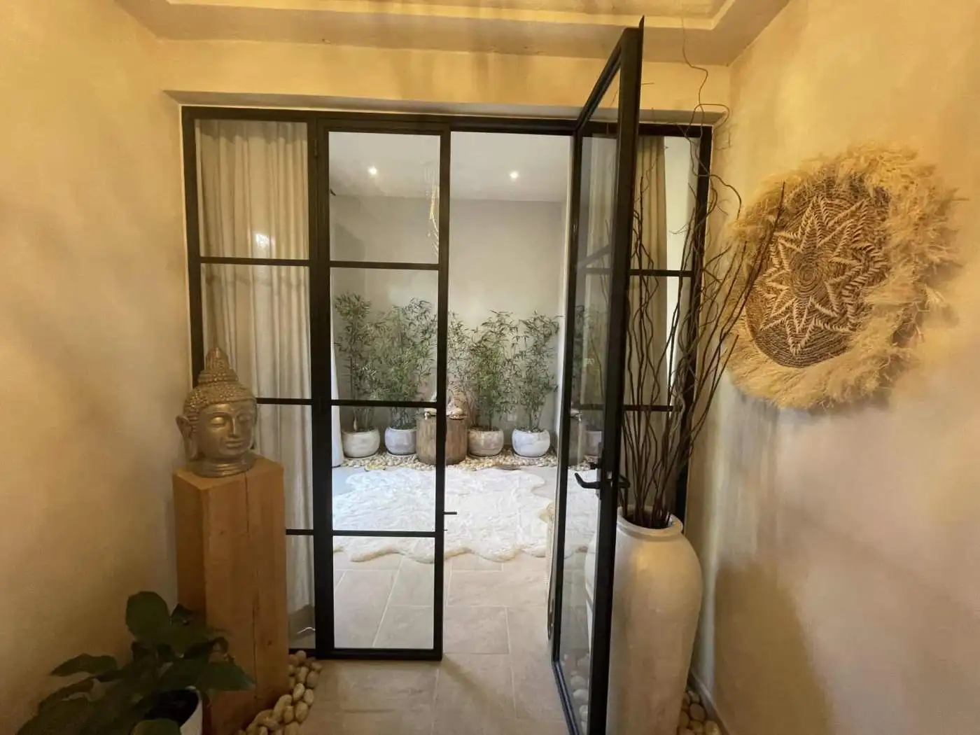 Elegant glass door leading to a serene outdoor patio with potted plants and natural decor.
