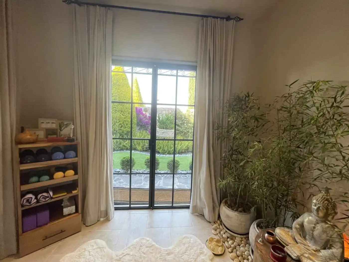 Garden view through sliding glass door with lush greenery and colorful flowers.