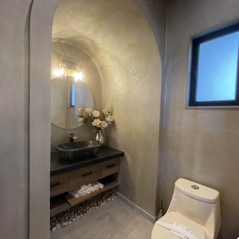 Modern bathroom with stone sink, minimalist decor, and natural lighting.