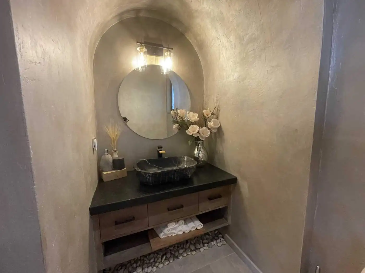 Modern bathroom vanity with stone sink, mirror, and floral decor for elegant interior design.