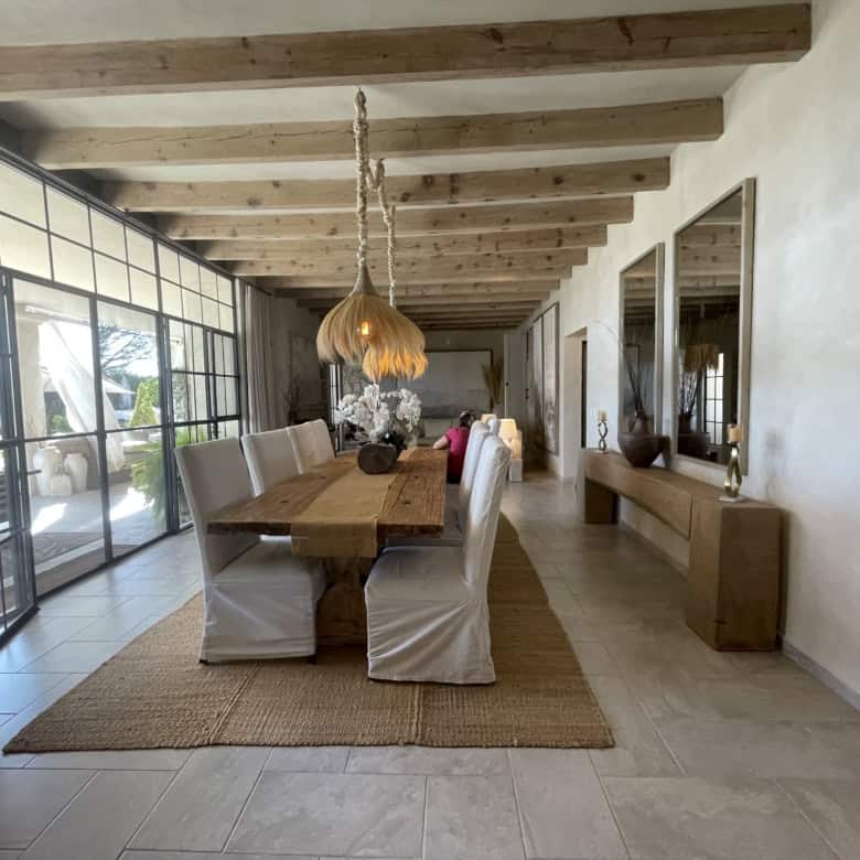 Spacious dining area featuring a wooden table, white chairs, and large windows with natural light.