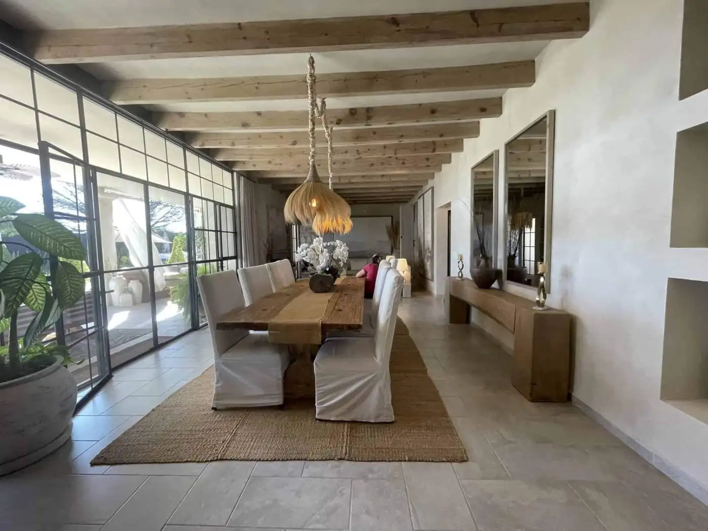 Spacious dining area featuring a wooden table, white chairs, and large windows with natural light.