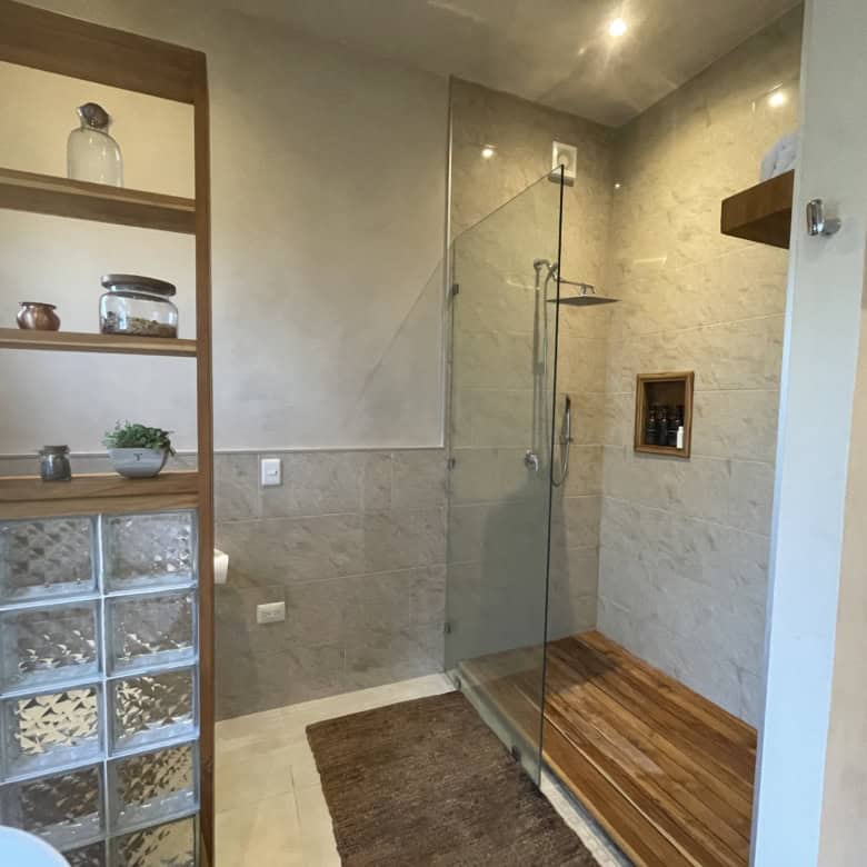 Modern bathroom with walk-in shower, glass partition, and wooden flooring accents.
