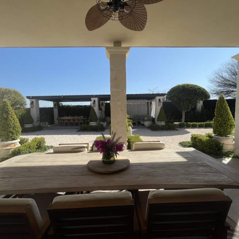 Outdoor patio with garden view, shaded seating, and decorative plants.