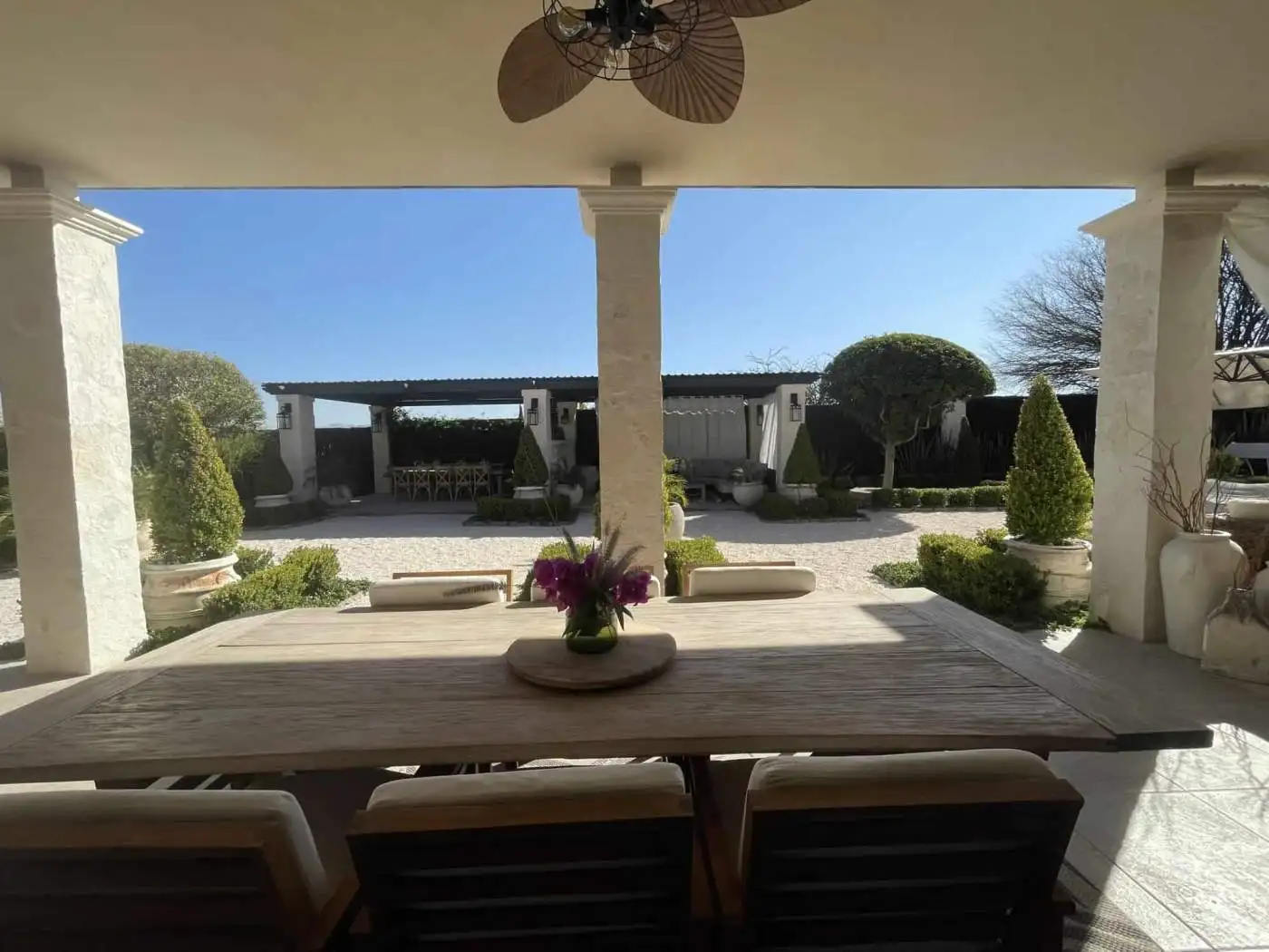 Outdoor patio with garden view, shaded seating, and decorative plants.