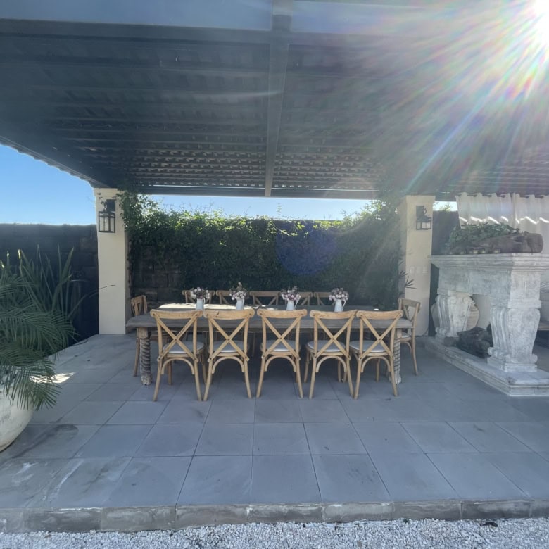 Outdoor dining space with shaded patio, stylish furniture, and lush greenery backdrop.