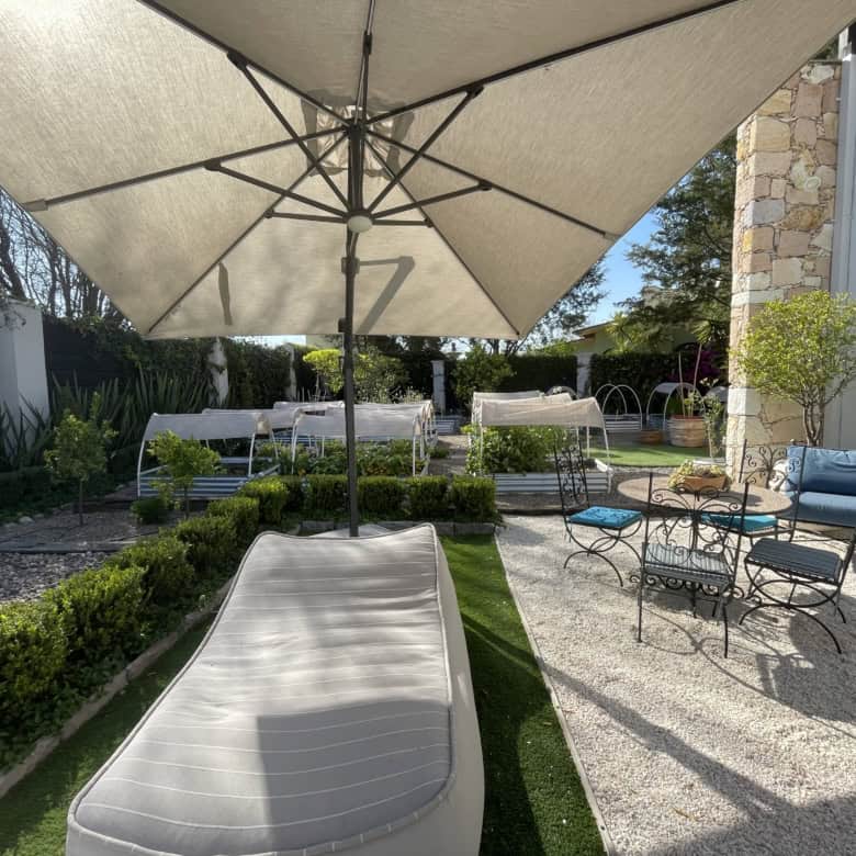 Outdoor patio with sun loungers, table, and chairs in a lush garden setting.