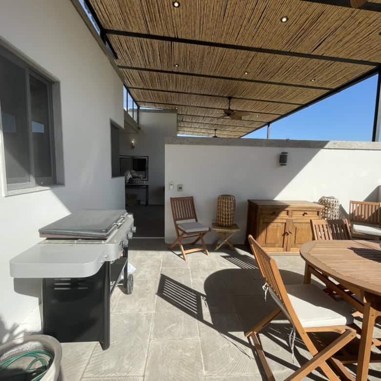 Outdoor rooftop terrace with seating, dining table, and BBQ setup for entertaining.
