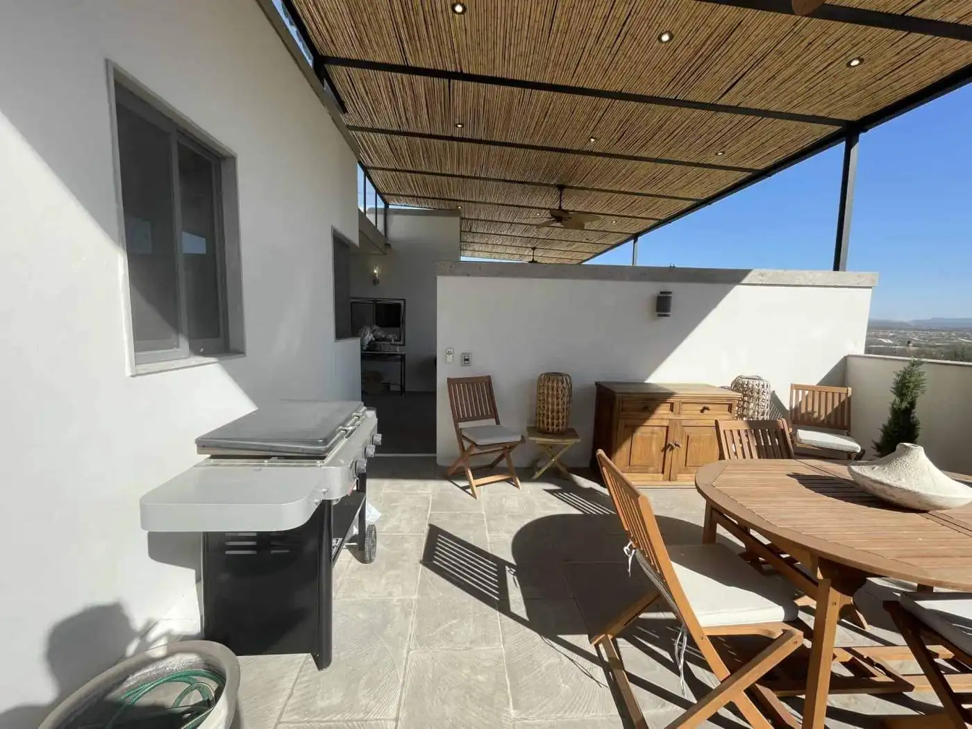 Outdoor rooftop terrace with seating, dining table, and BBQ setup for entertaining.
