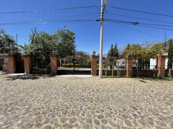 Brick gate entrance with iron fencing and lush greenery.