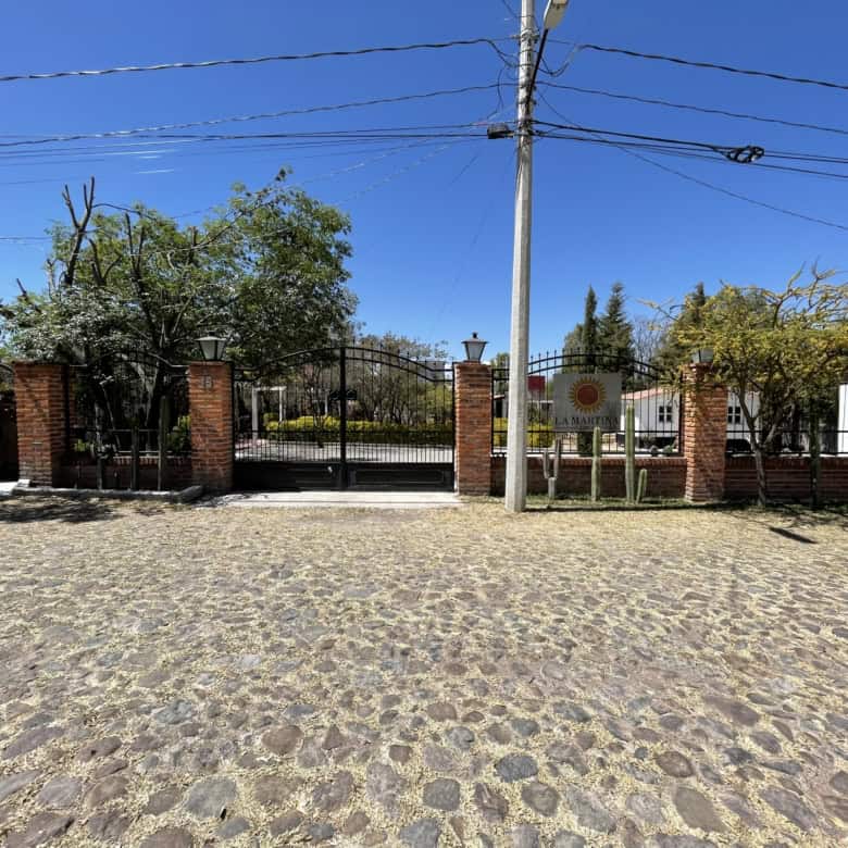 Brick gate entrance with iron fencing and lush greenery.