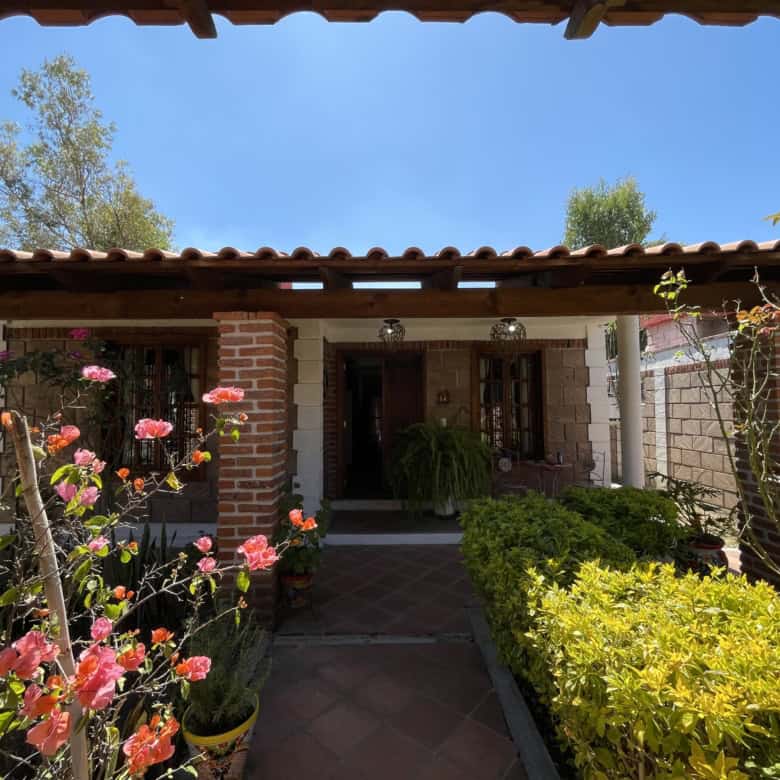 Beautiful garden entrance with blooming flowers and lush plants under a wooden pergola.
