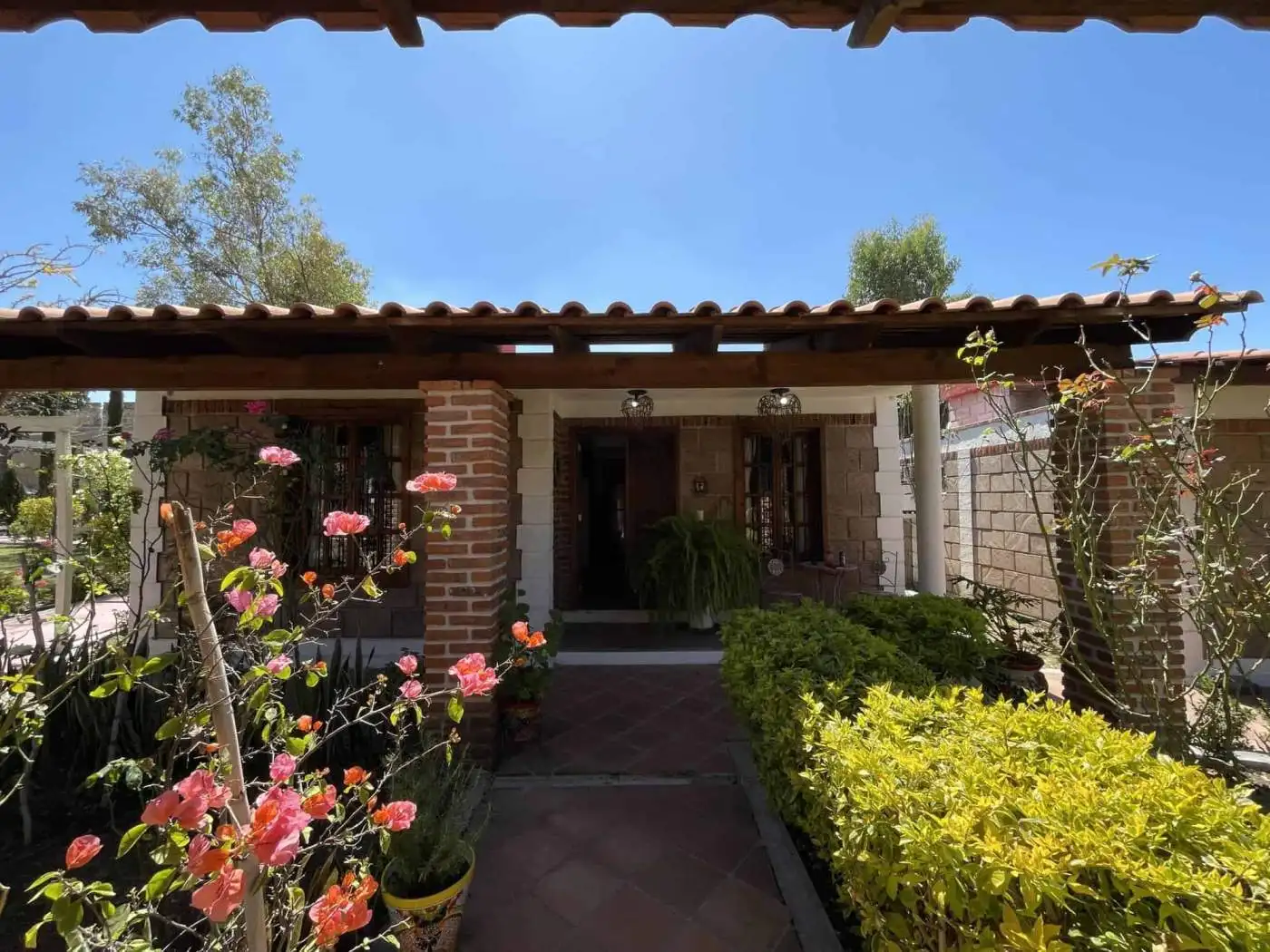 Beautiful garden entrance with blooming flowers and lush plants under a wooden pergola.