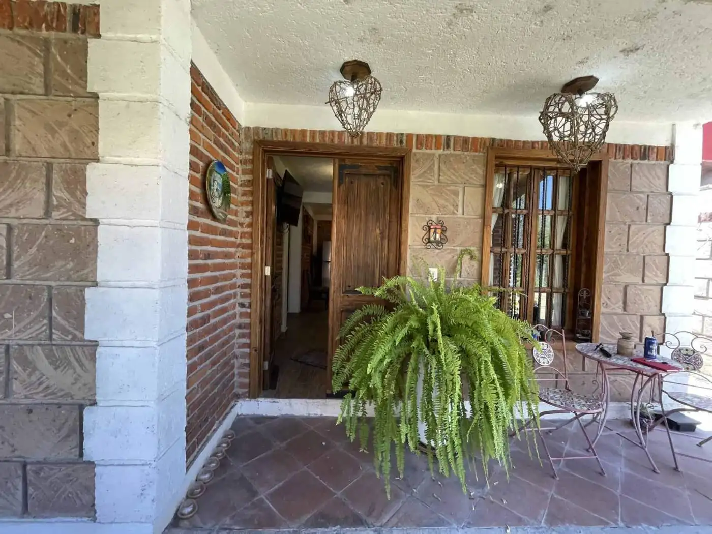 Beautiful outdoor porch featuring a vibrant fern and elegant seating area for relaxing or entertaini.