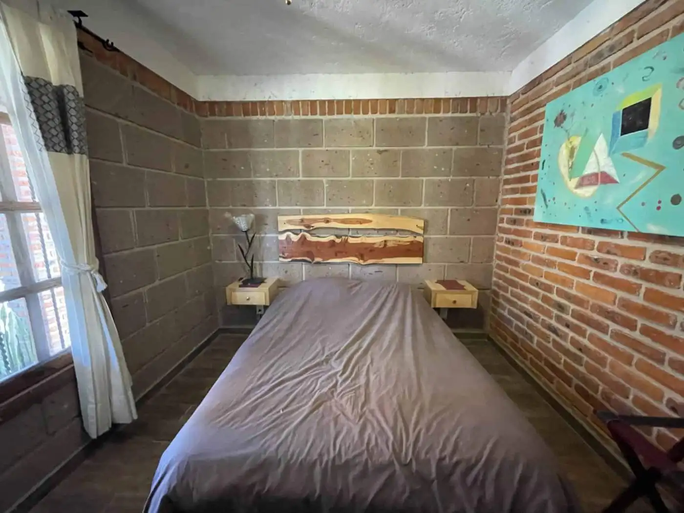 Modern bedroom with artistic wall art and natural light.