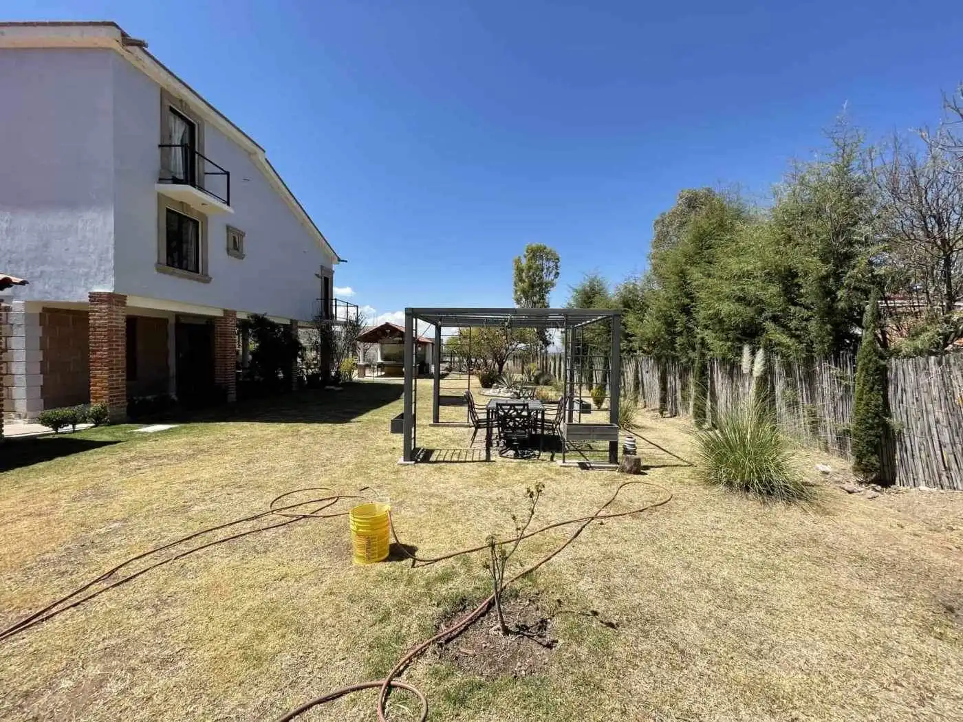 Spacious backyard featuring a garden, outdoor seating, and a pergola for relaxing outdoor activities.