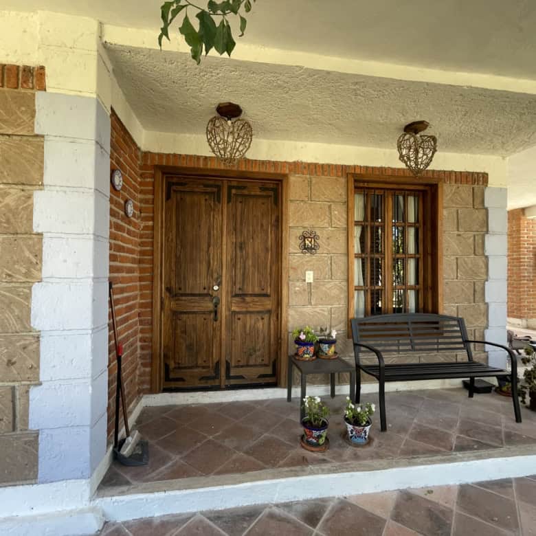 Beautiful house entrance with wooden door and garden seating area.