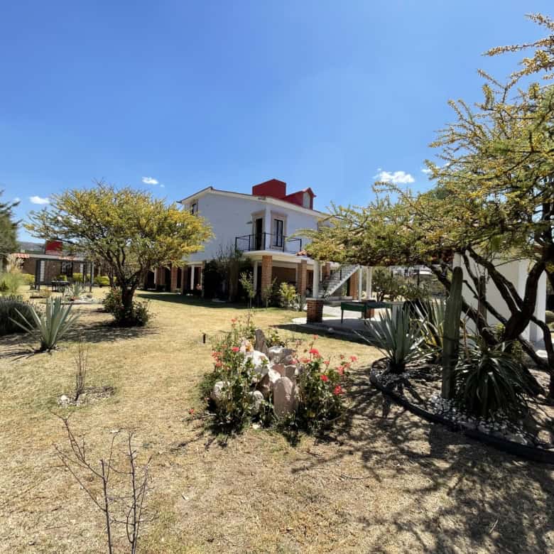 Luxury villa with garden and trees in a sunny outdoor setting.