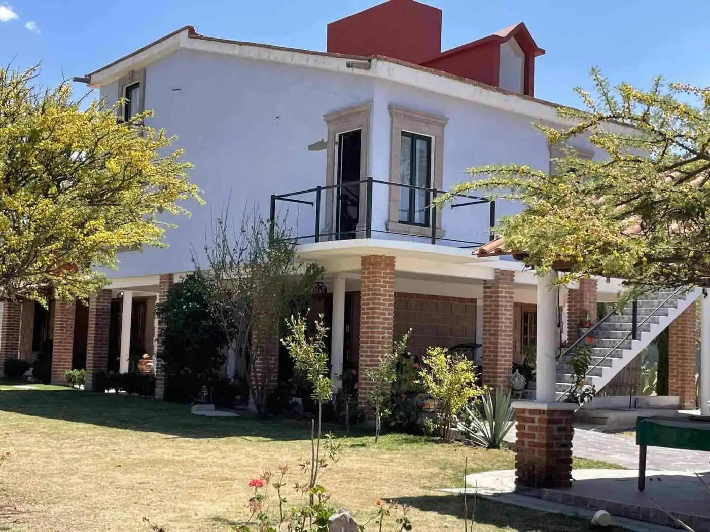 Contemporary two-story home with garden, outdoor staircase, and lush landscaping.